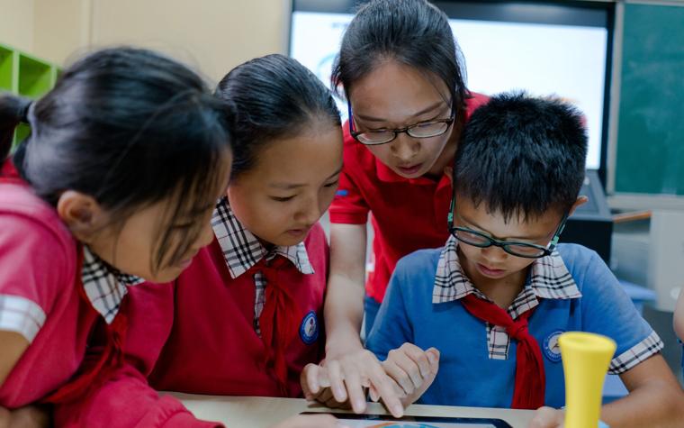 School children and a teacher looking at an tablet