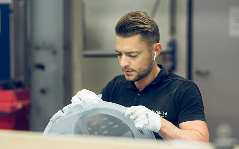 Ein Mann schleift ein 3D-gedrucktes Bauteil in einer Produktionsstätte von Materialise ab