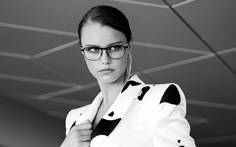 Female model holding her collar, looking off camera, and wearing dark eyewear from the Hoet Cabrio PR collection