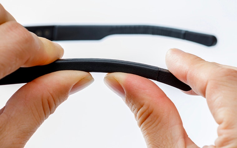 Close-up of a person holding arm of the Iristick Z1 glasses with two hands showing how the material bends