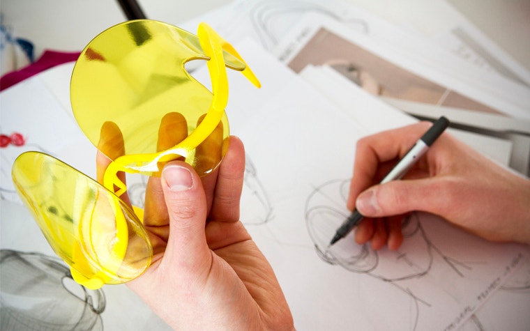 Dávid Ring holds 3D printed glasses in his left hand and draws on sketchpad with his right hand