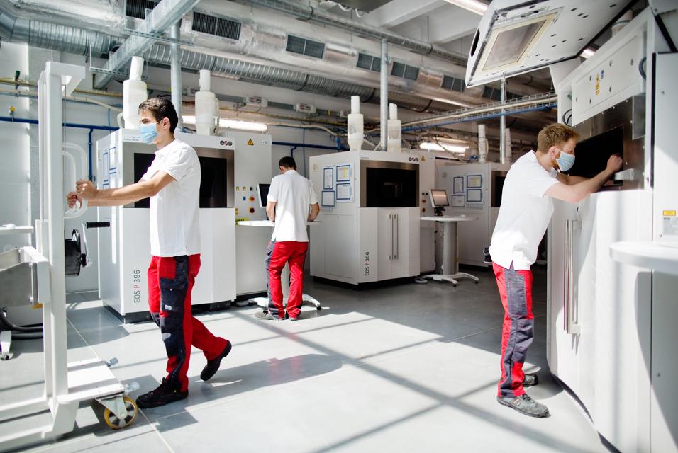 Materialise employees in a production facility working while wearing medical masks