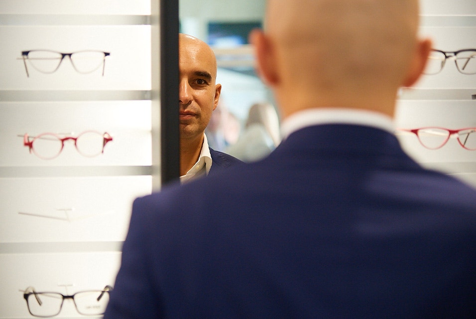 Man standing in front of a Yuniku 3D scanner in an eyewear store