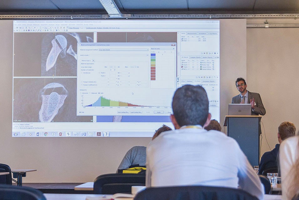 Instructeur debout devant la classe, enseignant l'utilisation de Mimics avec un écran d'ordinateur projeté au mur