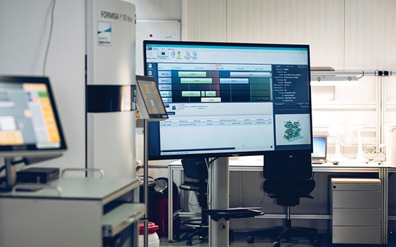 Grande schermo in un'area di produzione a sinterizzazione laser su cui è visualizzato il software di gestione della produzione Streamics