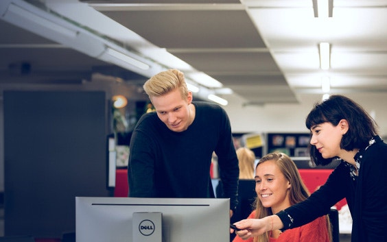 Three Materialise colleagues, one sitting and two standing, looking at a computer screen