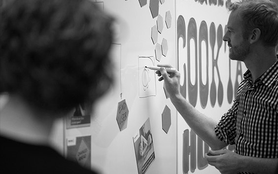 Looking at a man drawing on a whiteboard over the shoulder of a woman