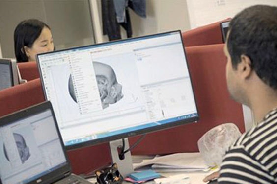 Man sitting at a desk, looking at Mimics software on his computer