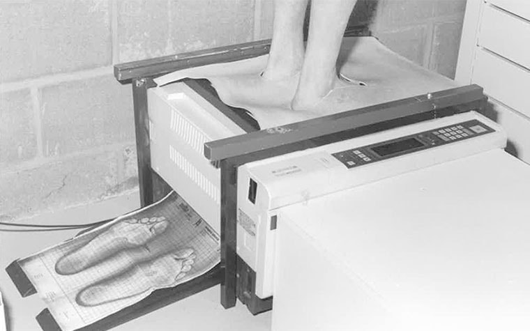 Person standing on a copy machine to measure their foot type
