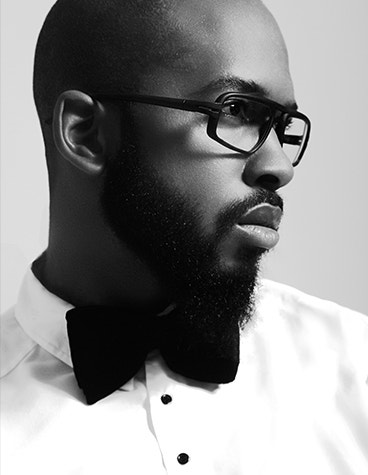 Gray-scale, side view of a black male model in formalwear wearing Hoet Cabrio eyeglasses