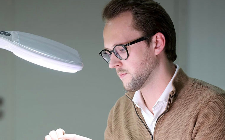 Man looking at a 3D-printed part under a light