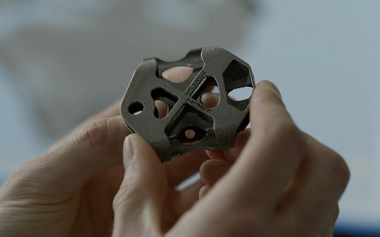 Person holding metal 3D-printed part for the Pinarello bike  