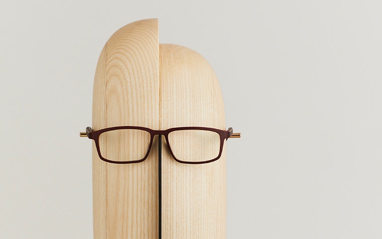 Yuniku+Ørgreen eyeglasses on a wooden stand