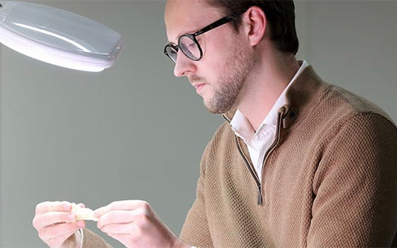 Man looking at a 3D-printed part under a light
