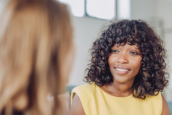 A woman smiling and talking to another woman