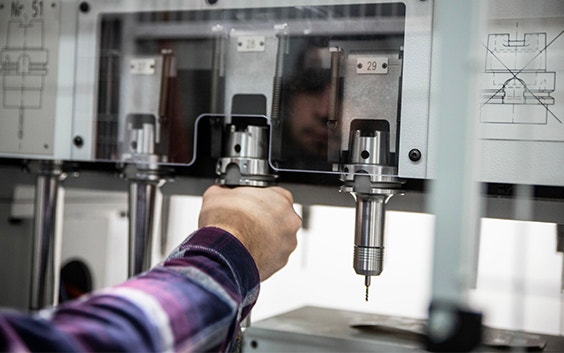 A hand adjusting a tool on equipment