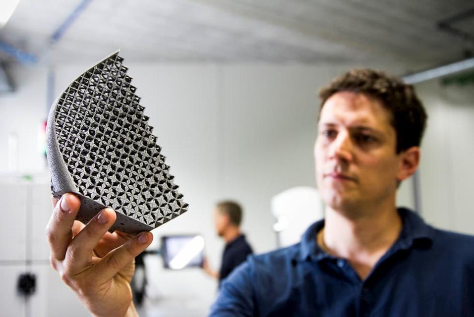 Man holding up a 3D-printed part and observing its structures