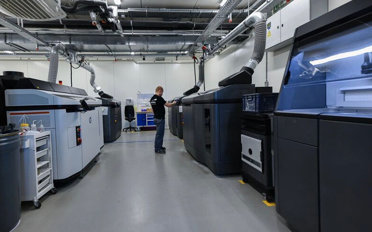 Ein Druckerbediener von Materialise macht Einstellungen auf einer MJF-Maschine in einem großen Druckerraum bei der Materialise-Zentrale in Leuven, Belgium