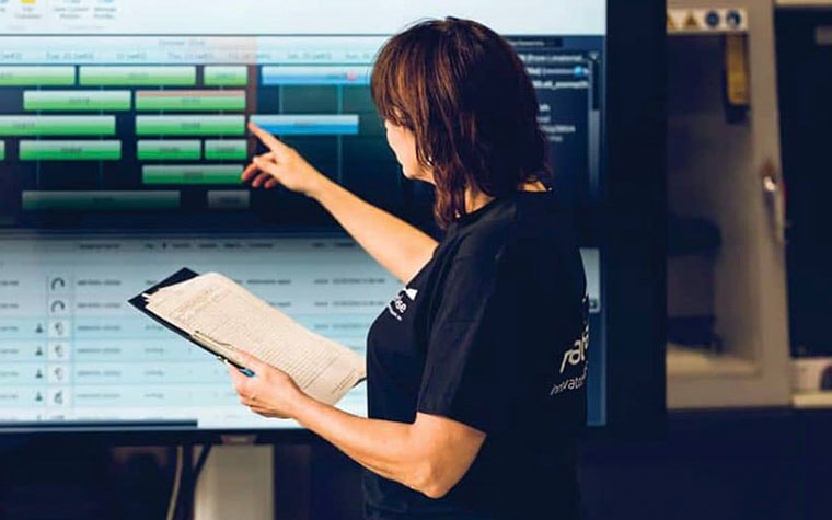 Woman pointing to a screen with Streamics showing production statuses