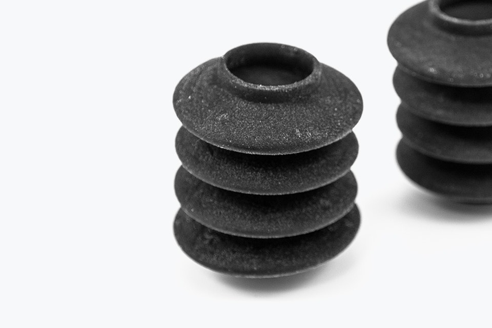 Nahaufnahme von zwei schwarzen 3D-gedruckten Blasebälgen aus Agilus, hergestellt mit PolyJet