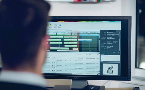 View over the shoulder of a man viewing production management software on a computer