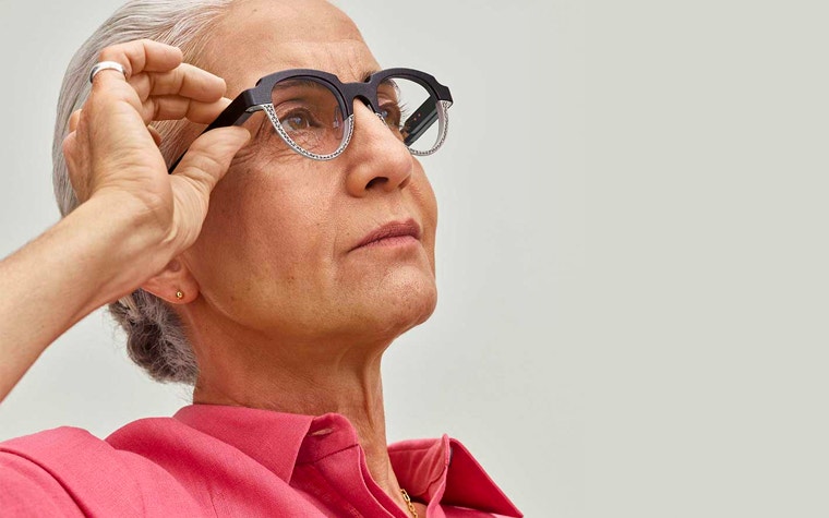 Woman wearing Morrow eyewear, pressing the autofocal button, and looking up