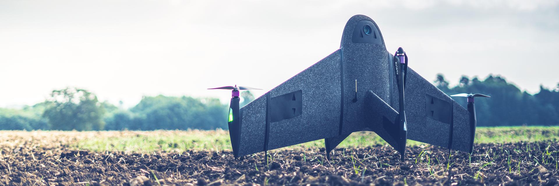 Un dron topográfico impreso en 3D en posición vertical sobre un campo embarrado.