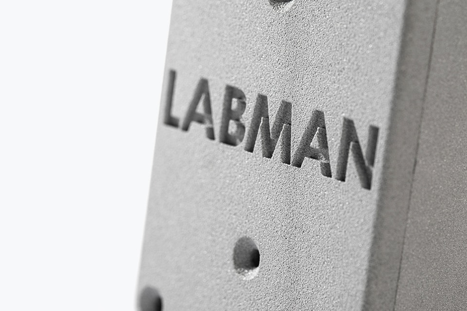 Bloque impreso en 3D en PA-AF con la palabra "LABMAN" grabada
