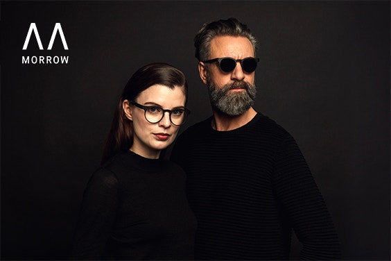 Männliche und weibliche Models in Schwarz auf schwarzem Hintergrund mit Brillen von Morrow Optics.