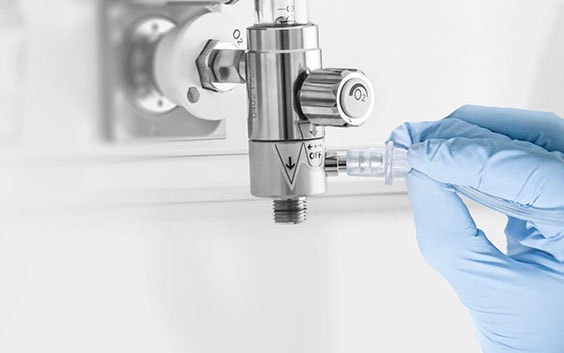 Gloved hand plugging a component into an oxygen gauge