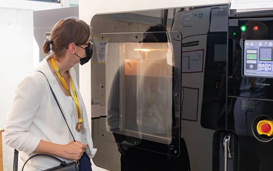 Woman looking into a 3D printer