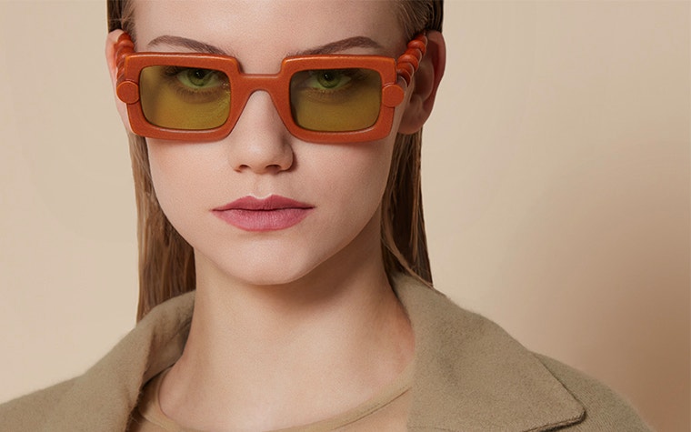 Modella che guarda nella fotocamera e indossa occhiali rettangolari rosso/arancio della collezione BAARS x GOGOSHA