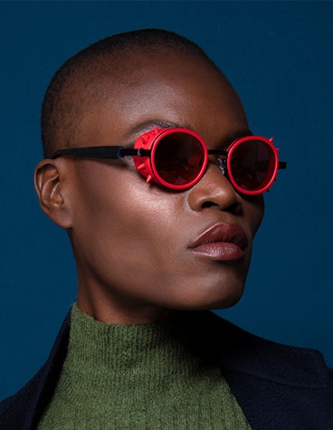 Nahaufnahme eines schwarzen weiblichen Models, das mit einer roten Sonnenbrille aus der ReyStudio NAUTINEW-Kollektion in die Kamera schaut.