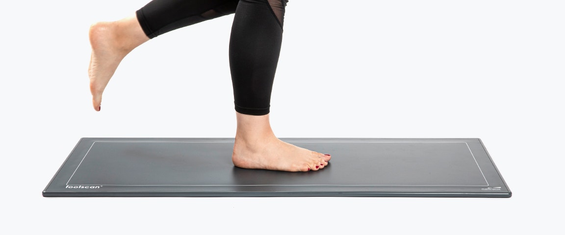 Person standing on a pressure plate with their right leg while the left leg is slightly lifted behind them