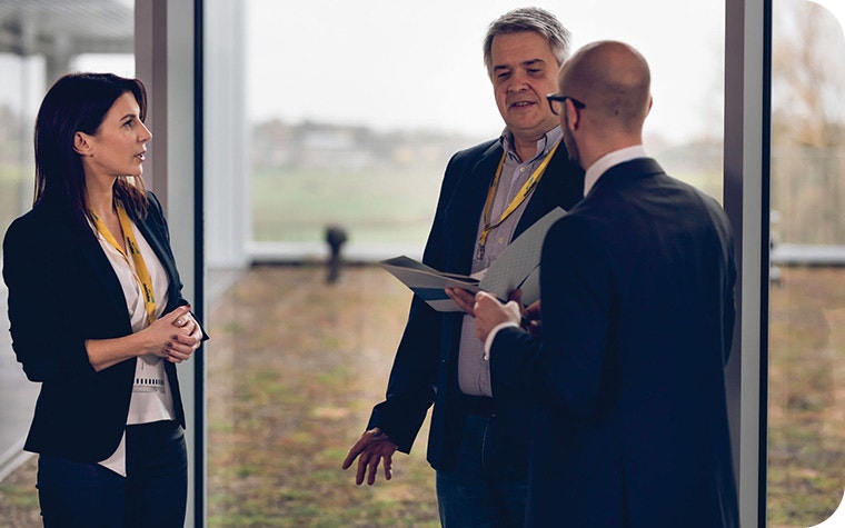 One woman and two men talking in business attire