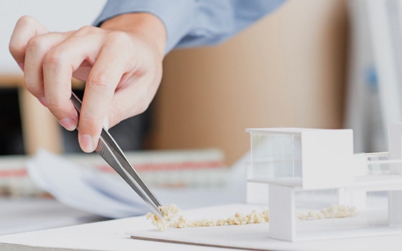 Person using tweezers to adjust pieces on an architectural model