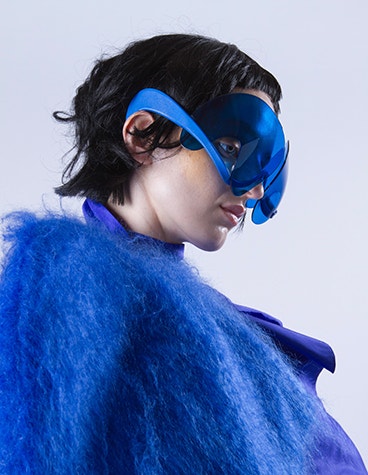 Model wearing a blue furry jacket and blue, artistic sunglasses designed by David Ring