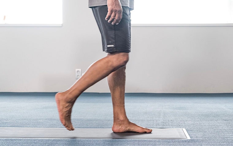 A man in shorts walks barefoot over a footscan pressure plate.