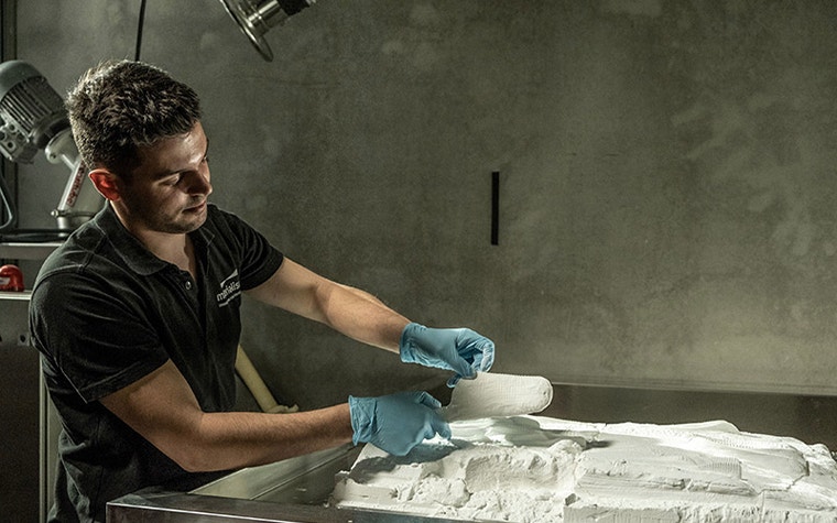 Man removing a 3D-printed insole from a powder bed