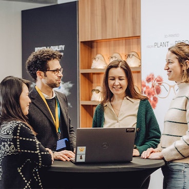 A close up image of a group of people having a stand-up meeting around a table