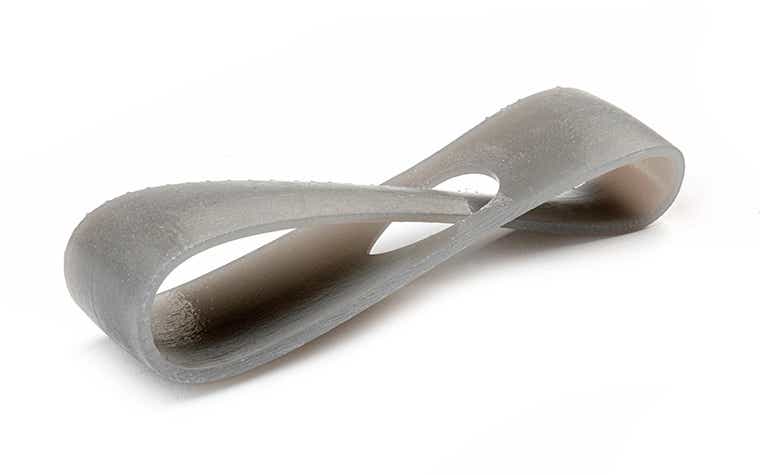 Un anello grigio chiaro stampato in 3D con Tusk Somos SolidGrey 3000 in stereolitografia, con finitura di base.