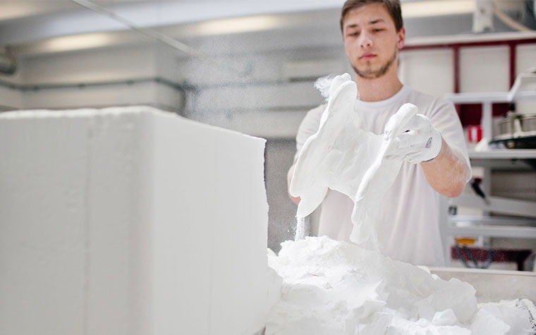 Man removing 3D-printed insoles from a powder bed