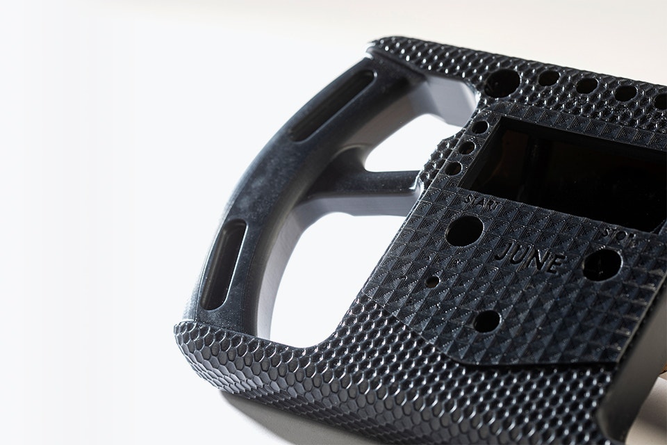 Close up of a black 3D-printed racing-style steering wheel made in Taurus using stereolithography.
