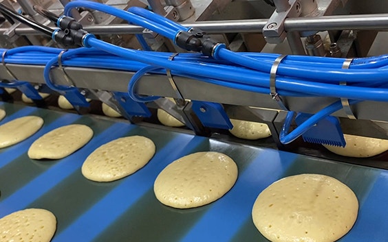 Pancake batter being poured out in a production line