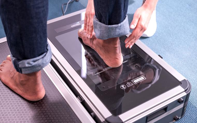 A clinical specialist measuring a patient's feet using a footscan machine