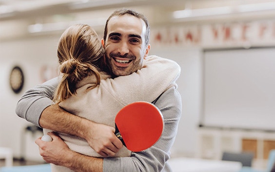 A man and a woman at Materialsie hugging with a ping pong paddle in hand