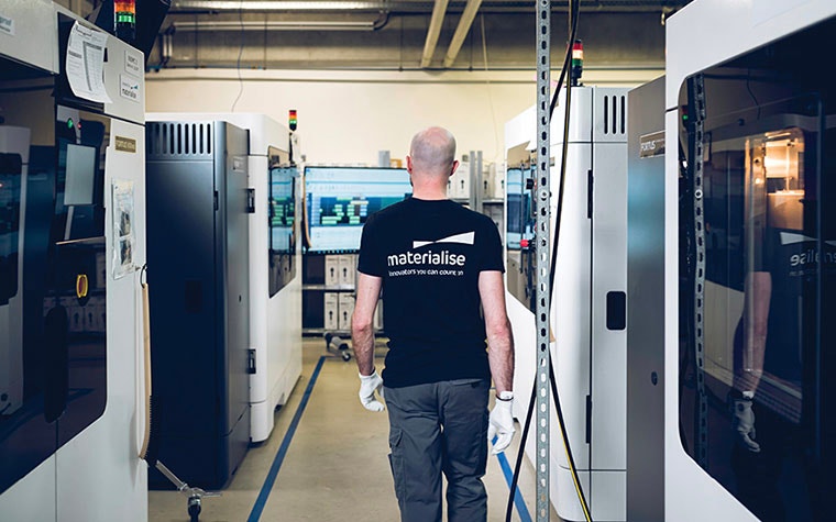 Man walking through a production facility full of 3D printers