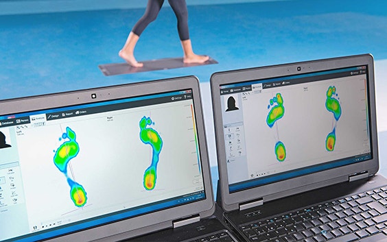 Fußvermessungssoftware mit einer Person, die auf einem Fußscan im Hintergrund läuft