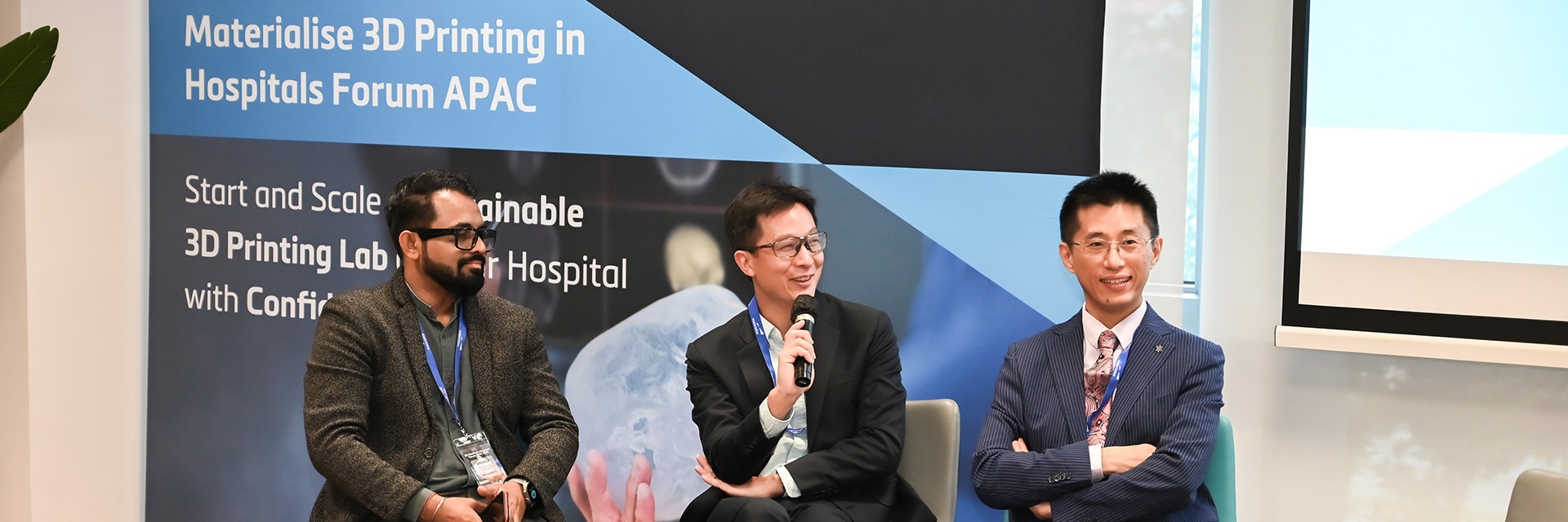 A group of 3 men sitting in chairs at the conference.