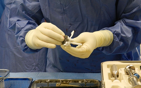 Member of operating theatre team holds Glenius implant and surgical guides